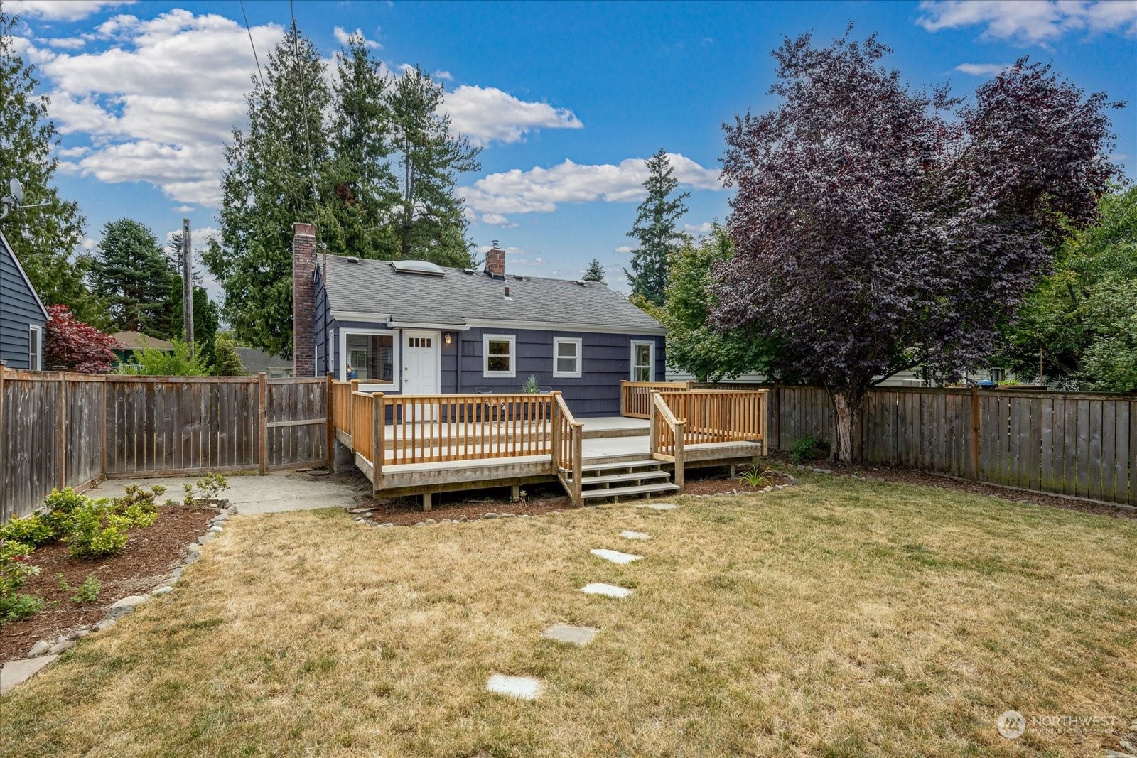 4839 50th Avenue Southwest Seattle, WA 98116 - Photo 26 of 31 a white house that has a small yard and a wooden fence