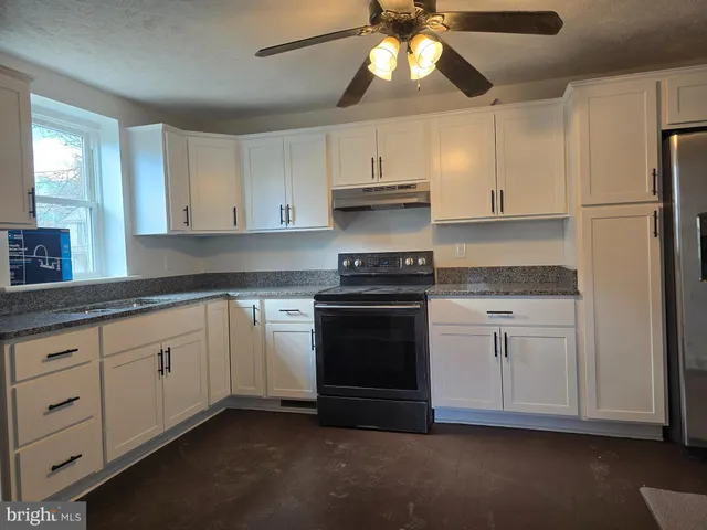 a kitchen with granite countertop white cabinets and stainless steel appliances