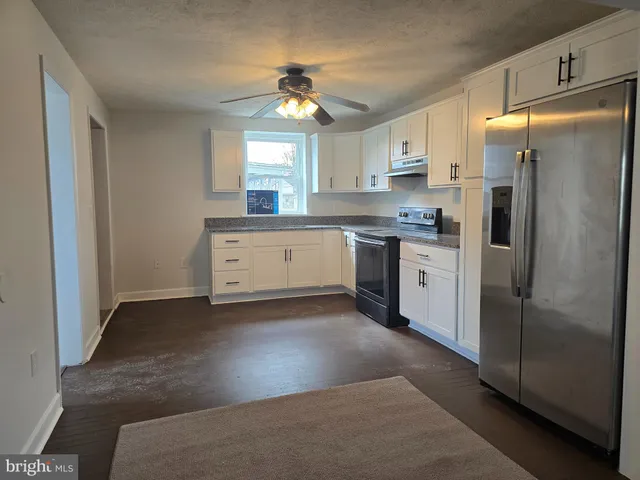 a kitchen with stainless steel appliances granite countertop a refrigerator a sink dishwasher a stove and white countertops with wooden floor