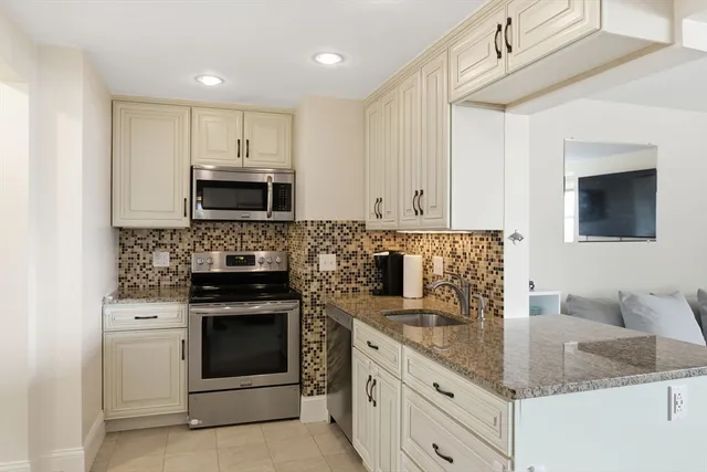a kitchen with granite countertop a stove top oven microwave and cabinets