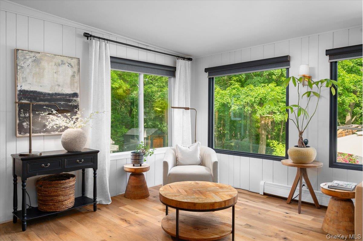 13 Jacks Pond Road Newburgh, NY 12550 - Photo 17 of 44 Warm and welcoming, this interior living space showcases wide-plank wood-finish flooring and classic white vertical paneling—ideal for relaxing with a book.