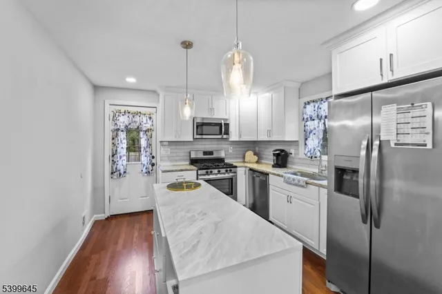 a kitchen with refrigerator a microwave a stove and white cabinets with wooden floor