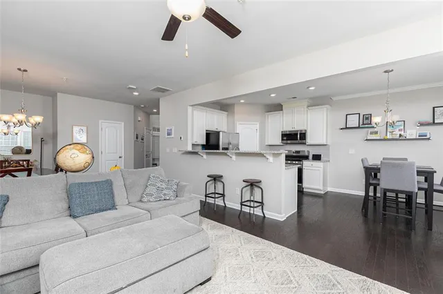 a living room with furniture kitchen view and a wooden floor