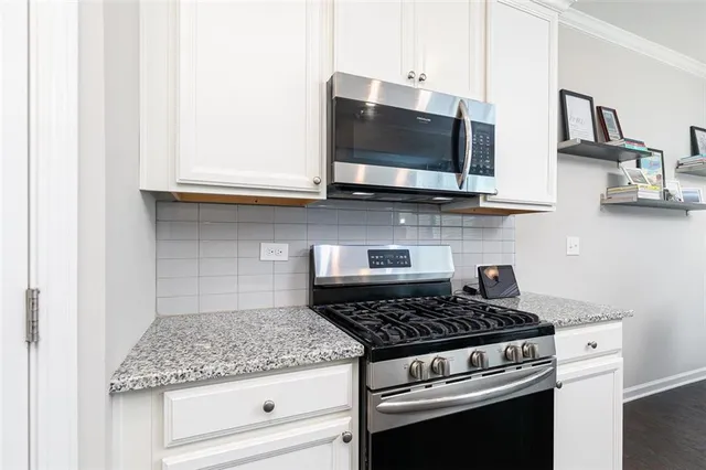 a kitchen with stainless steel appliances granite countertop white cabinets and black stove top