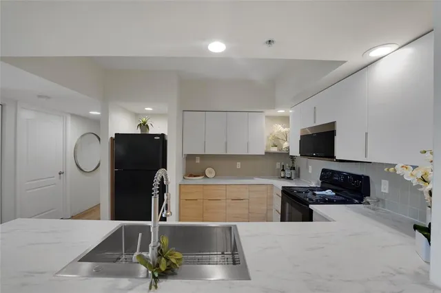 a kitchen with stainless steel appliances kitchen island granite countertop a refrigerator a stove a microwave oven a sink with island and chairs