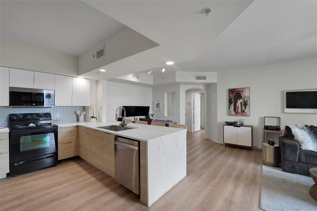 100 North Federal Highway, Unit 819 Fort Lauderdale, FL 33301 - Photo 4 of 36 a open kitchen with stainless steel appliances a stove top oven a sink dishwasher a dining table and chairs with wooden floor