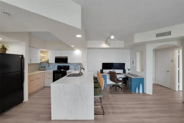 a living room with stainless steel appliances furniture and a flat screen tv