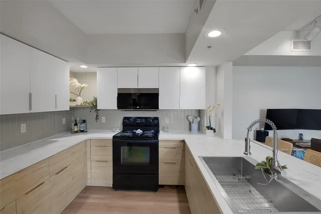 a kitchen with stainless steel appliances a stove a sink a stove a microwave a refrigerator and cabinets