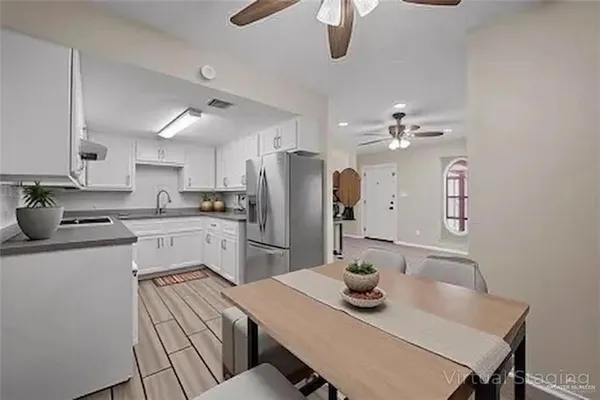an empty room with wooden floor chandelier fan and windows