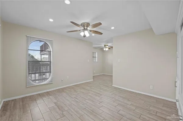 a view of an empty room with window and wooden floor