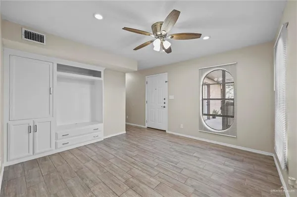 an empty room with a window and a chandelier fan