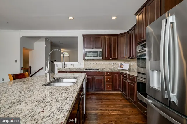 a kitchen with stainless steel appliances kitchen island granite countertop a stove a refrigerator and wooden cabinets