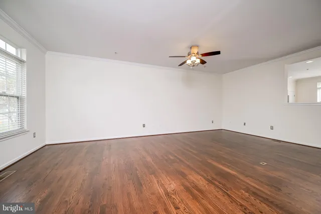 a view of an empty room with wooden floor and staircase
