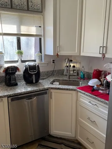 a kitchen with granite countertop a sink dishwasher stove and cabinets