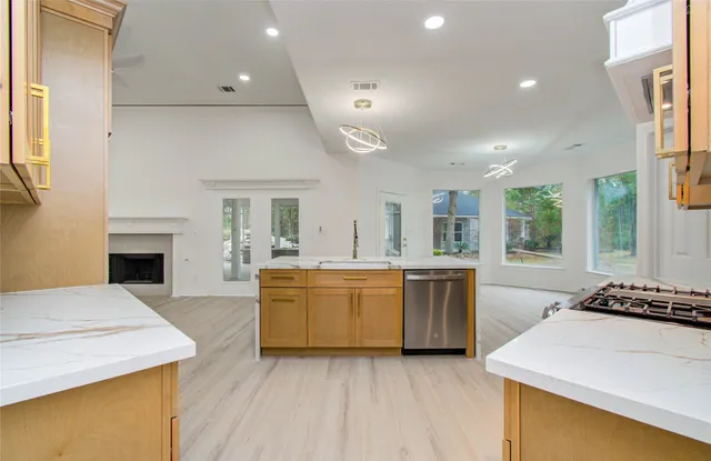 a large kitchen with a stove top oven a sink dishwasher and a fireplace with wooden floor