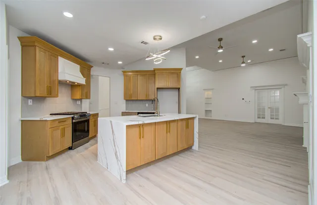 a large kitchen with stainless steel appliances granite countertop a large stove a sink dishwasher and a refrigerator with wooden floor