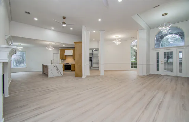 a view of an empty room with wooden floor and a kitchen
