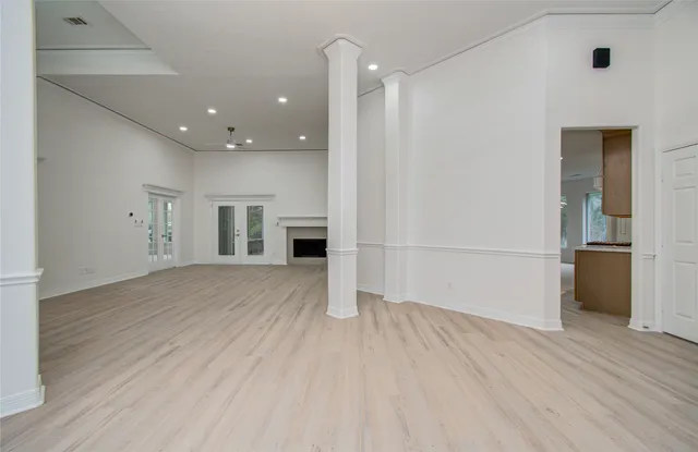 an empty room with wooden floor and kitchen view