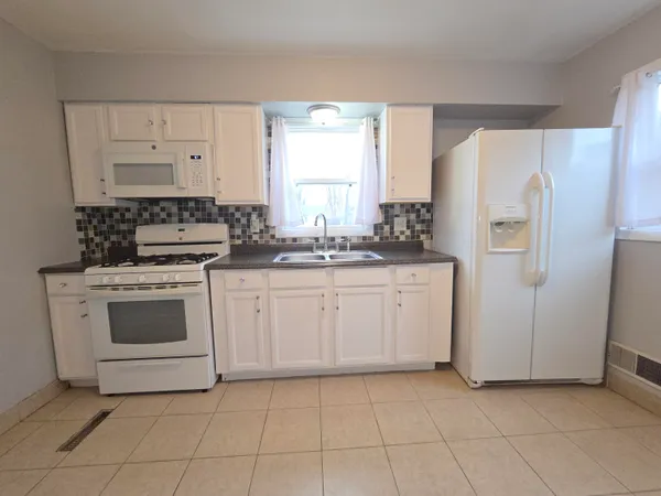 a kitchen with white cabinets and white appliances