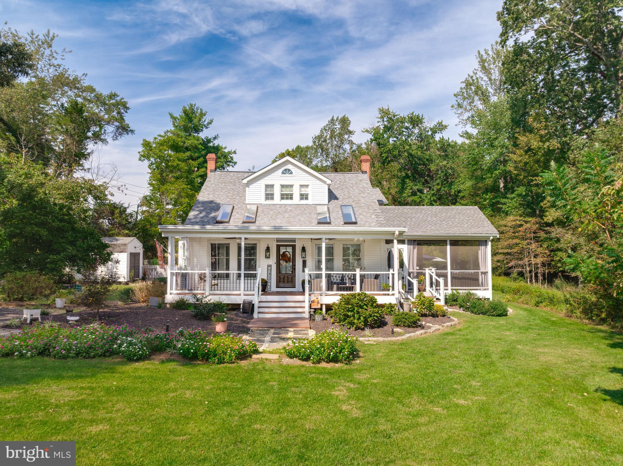 a front view of a house with a garden and trees