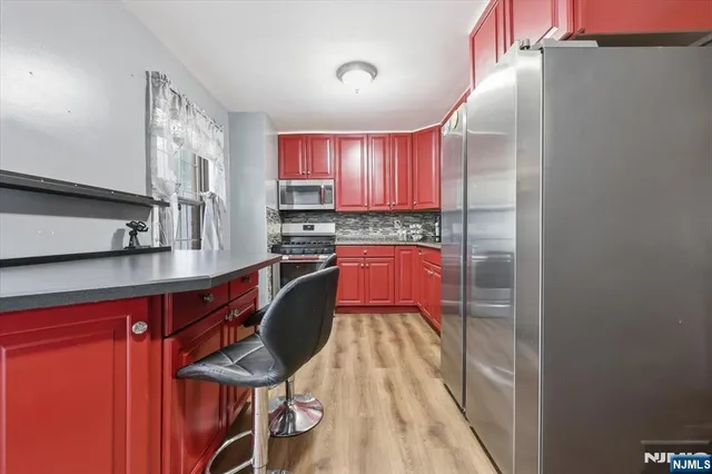 a kitchen with stainless steel appliances granite countertop a sink dishwasher a microwave oven a dining table and chairs with wooden floor