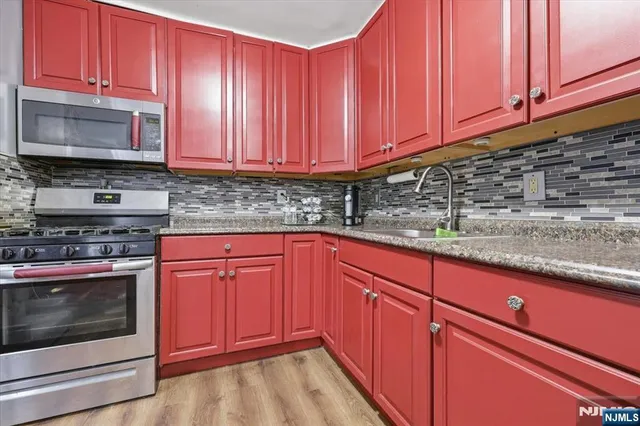 a kitchen with stainless steel appliances granite countertop wooden cabinets a stove and a sink
