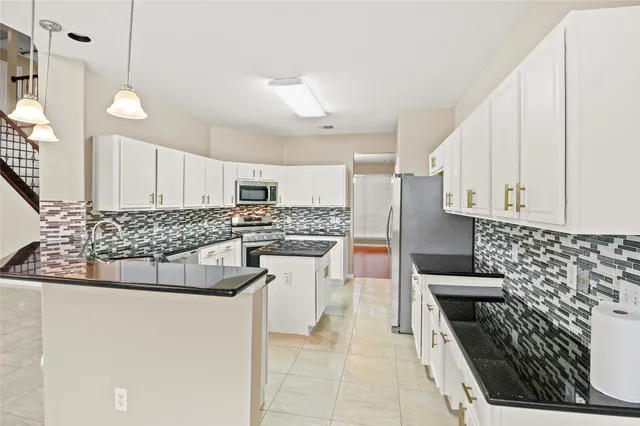 a kitchen with stainless steel appliances granite countertop a stove a sink and a refrigerator