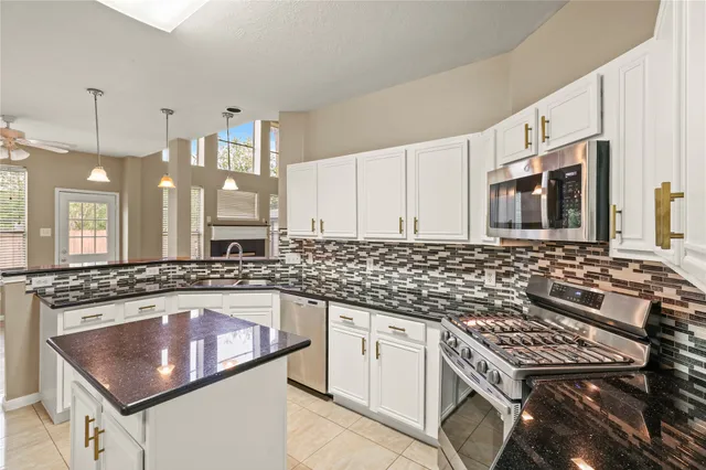a kitchen with stainless steel appliances kitchen island granite countertop a refrigerator a stove and white cabinets