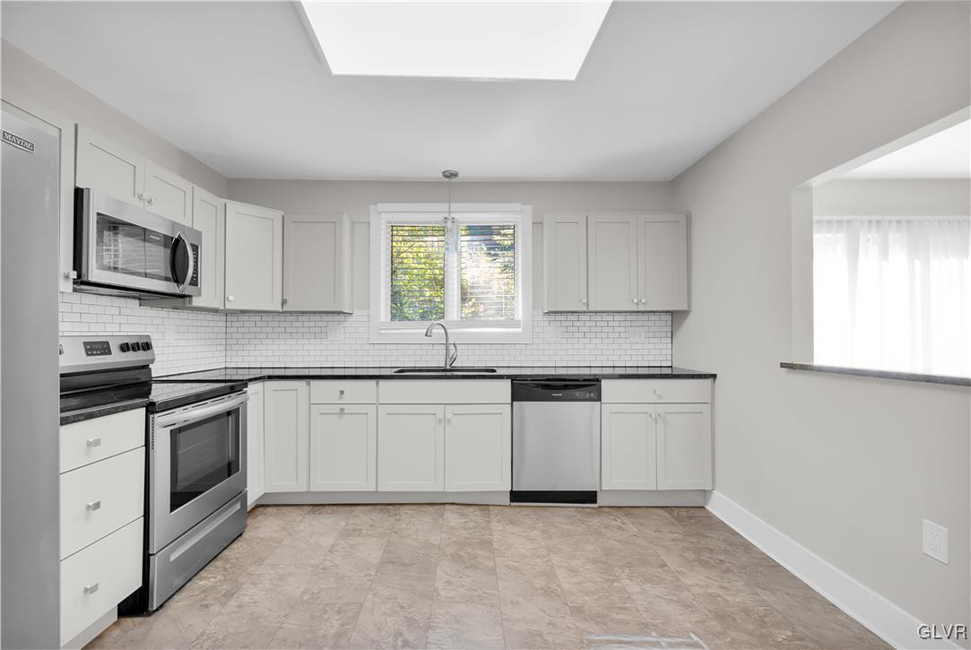 820 Morvale Road Easton, PA 18042 - Photo 23 of 50 a kitchen with granite countertop white cabinets a sink a window and stainless steel appliances