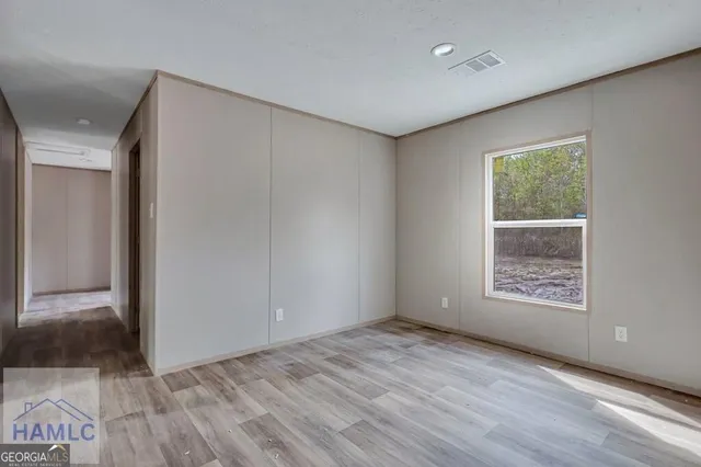 a view of an empty room with a window and wooden floor