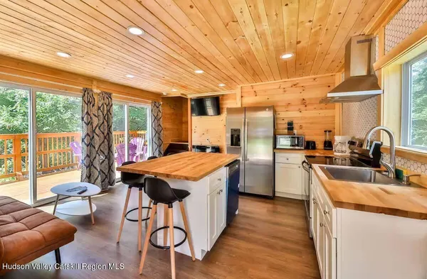 a view of a kitchen with kitchen island a large window cabinets a sink and stainless steel appliances