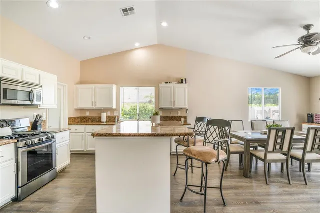 a kitchen with stainless steel appliances a table chairs refrigerator and cabinets