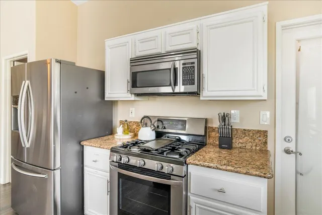 a kitchen with stainless steel appliances granite countertop white cabinets and a refrigerator