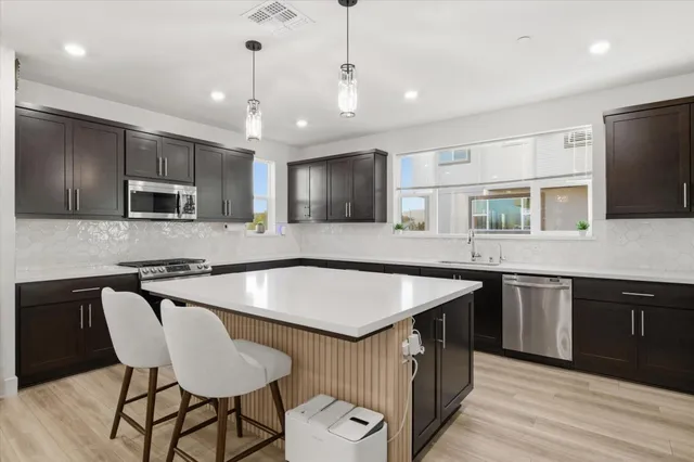 a kitchen with stainless steel appliances granite countertop a sink a stove a microwave and island