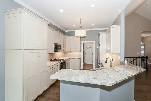 a kitchen with stainless steel appliances granite countertop a sink dishwasher a refrigerator white cabinets and wooden floor