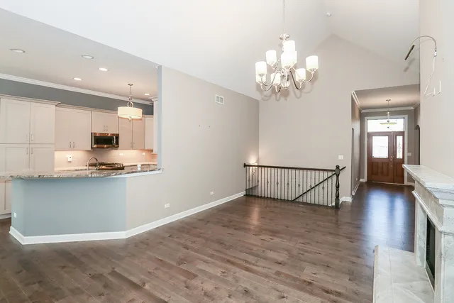 a view of a kitchen with granite countertop wooden floor stainless steel appliances and a chandelier