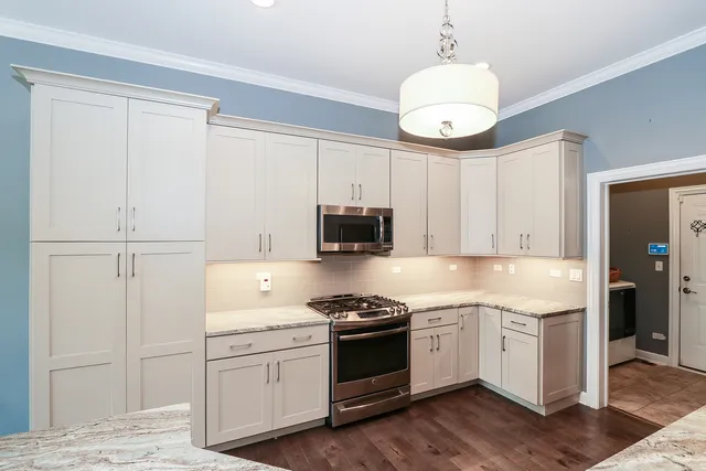a kitchen with cabinets stainless steel appliances and wooden floor