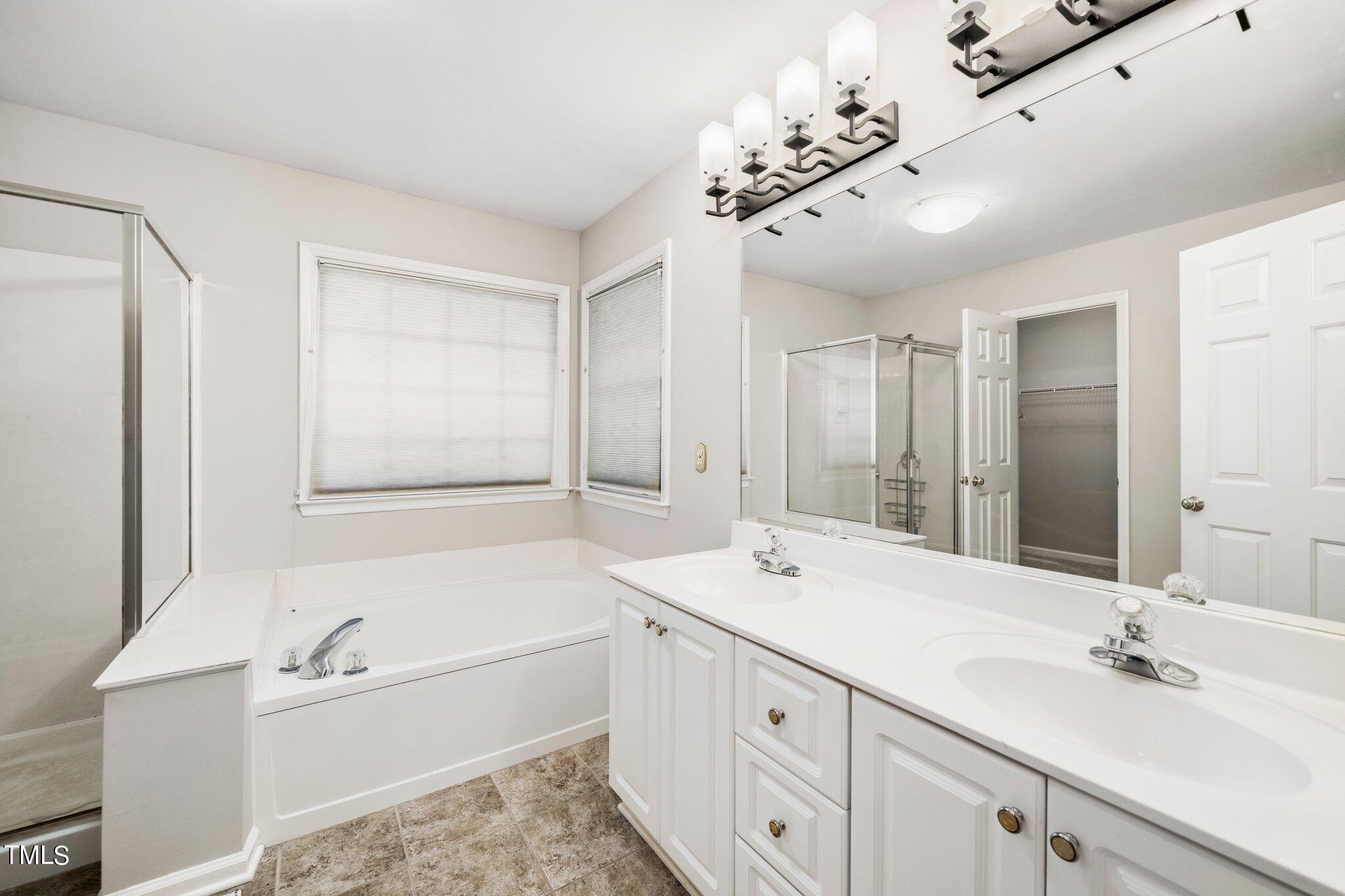 12216 Freemont Lane Raleigh, NC 27613 - Photo 16 of 23 a bathroom with a tub a sink double vanity and a mirror