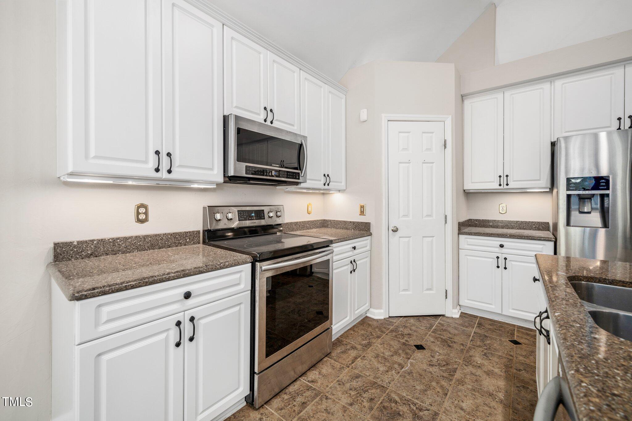 12216 Freemont Lane Raleigh, NC 27613 - Photo 7 of 23 a kitchen with stainless steel appliances granite countertop a stove a sink and a refrigerator