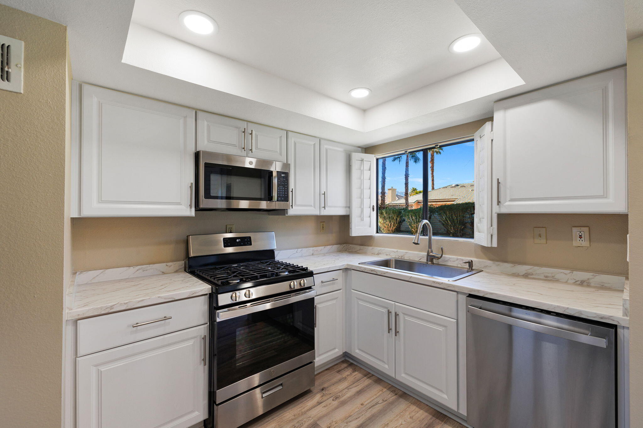 41045 Largo Palm Desert, CA 92211 - Photo 16 of 46 a kitchen with granite countertop a sink dishwasher stove and microwave with wooden cabinets