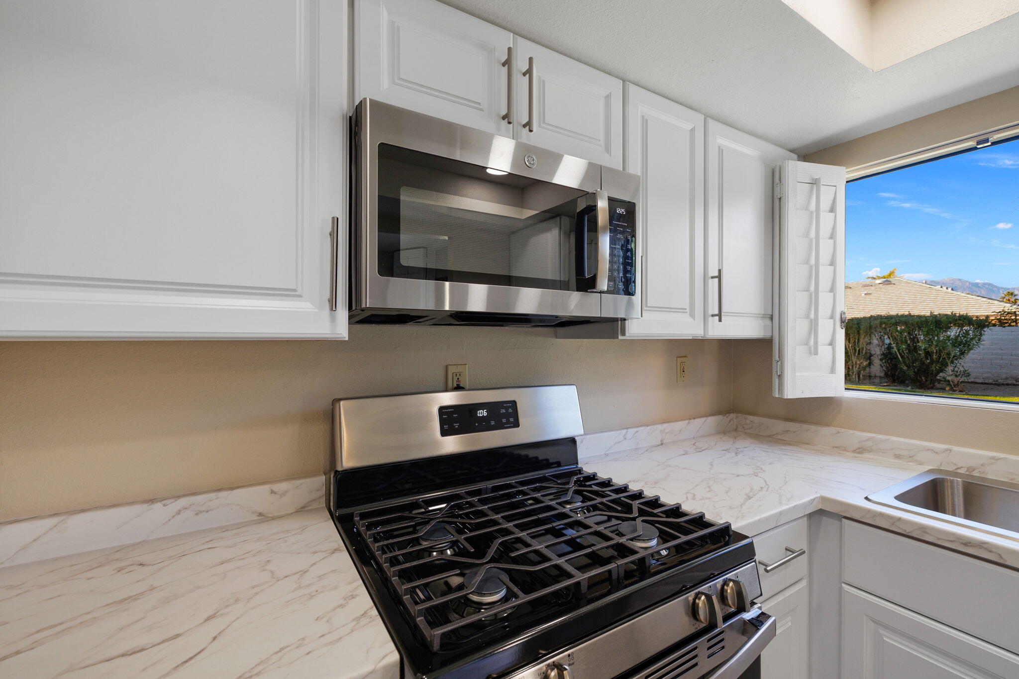 41045 Largo Palm Desert, CA 92211 - Photo 19 of 46 a kitchen with stainless steel appliances a stove a microwave and cabinets