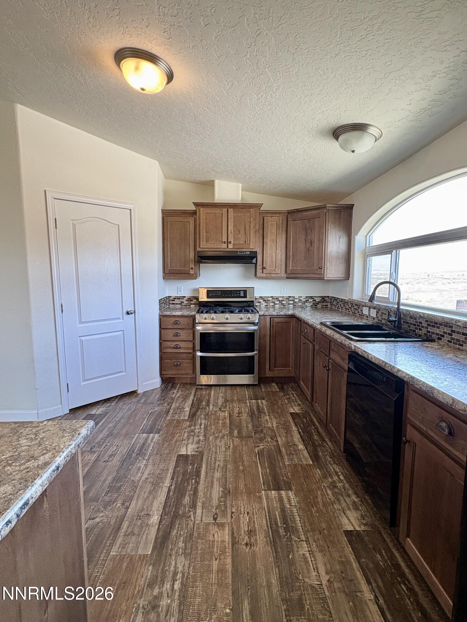 1415 Van Diest Road Winnemucca, NV 89445 - Photo 11 of 34 a kitchen with wooden floors and wooden cabinets