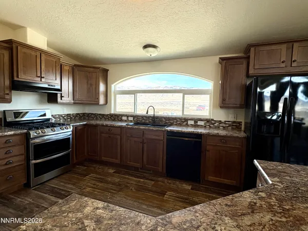 a kitchen with granite countertop a stove and cabinets