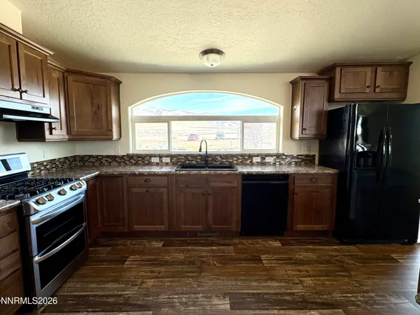a kitchen with stainless steel appliances granite countertop a stove and a wooden floors