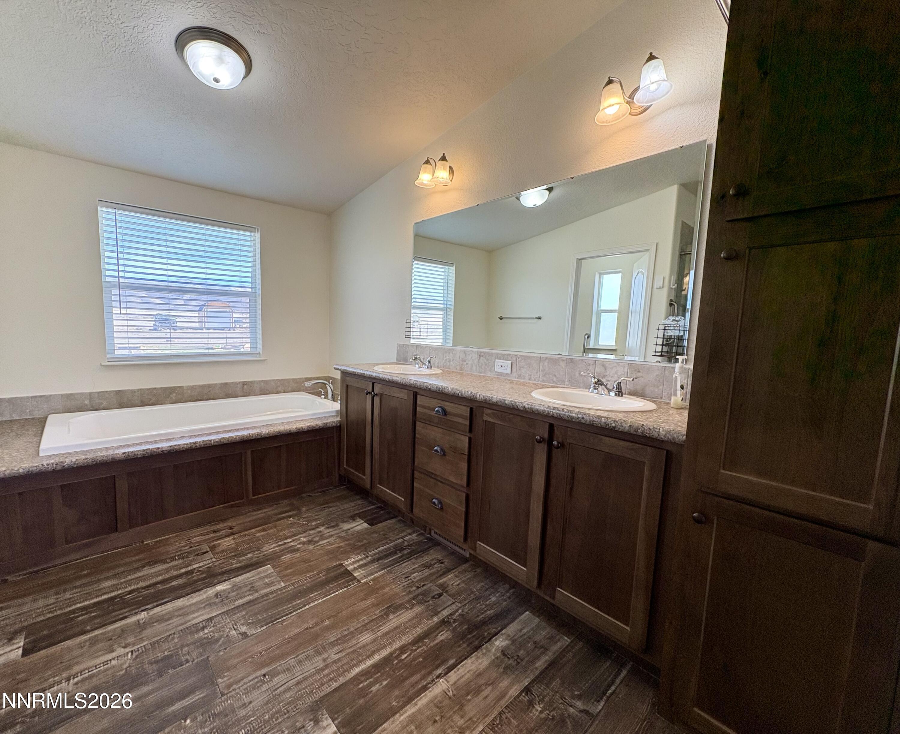 1415 Van Diest Road Winnemucca, NV 89445 - Photo 21 of 34 a bathroom with a double vanity sink a mirror and a bathtub