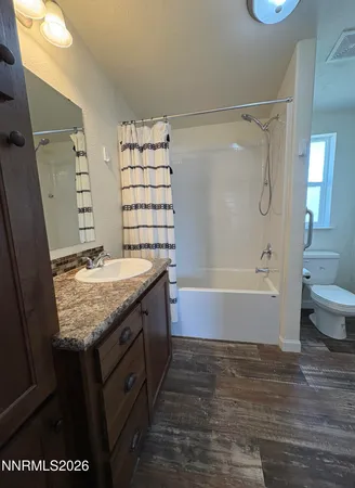 a bathroom with a granite countertop sink a toilet and shower