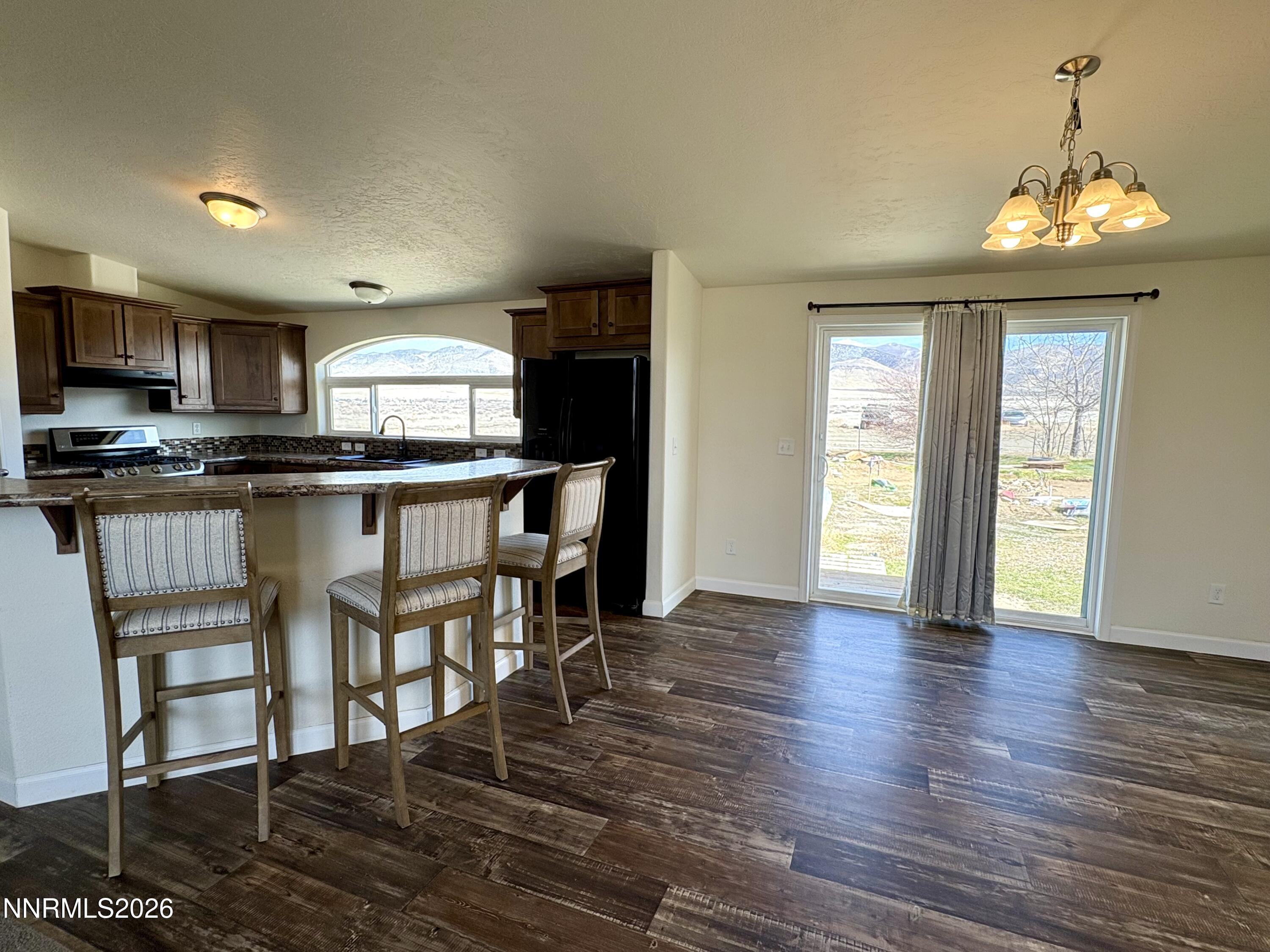 1415 Van Diest Road Winnemucca, NV 89445 - Photo 9 of 34 a kitchen with stainless steel appliances granite countertop a stove top oven a sink dishwasher and a refrigerator with wooden floor