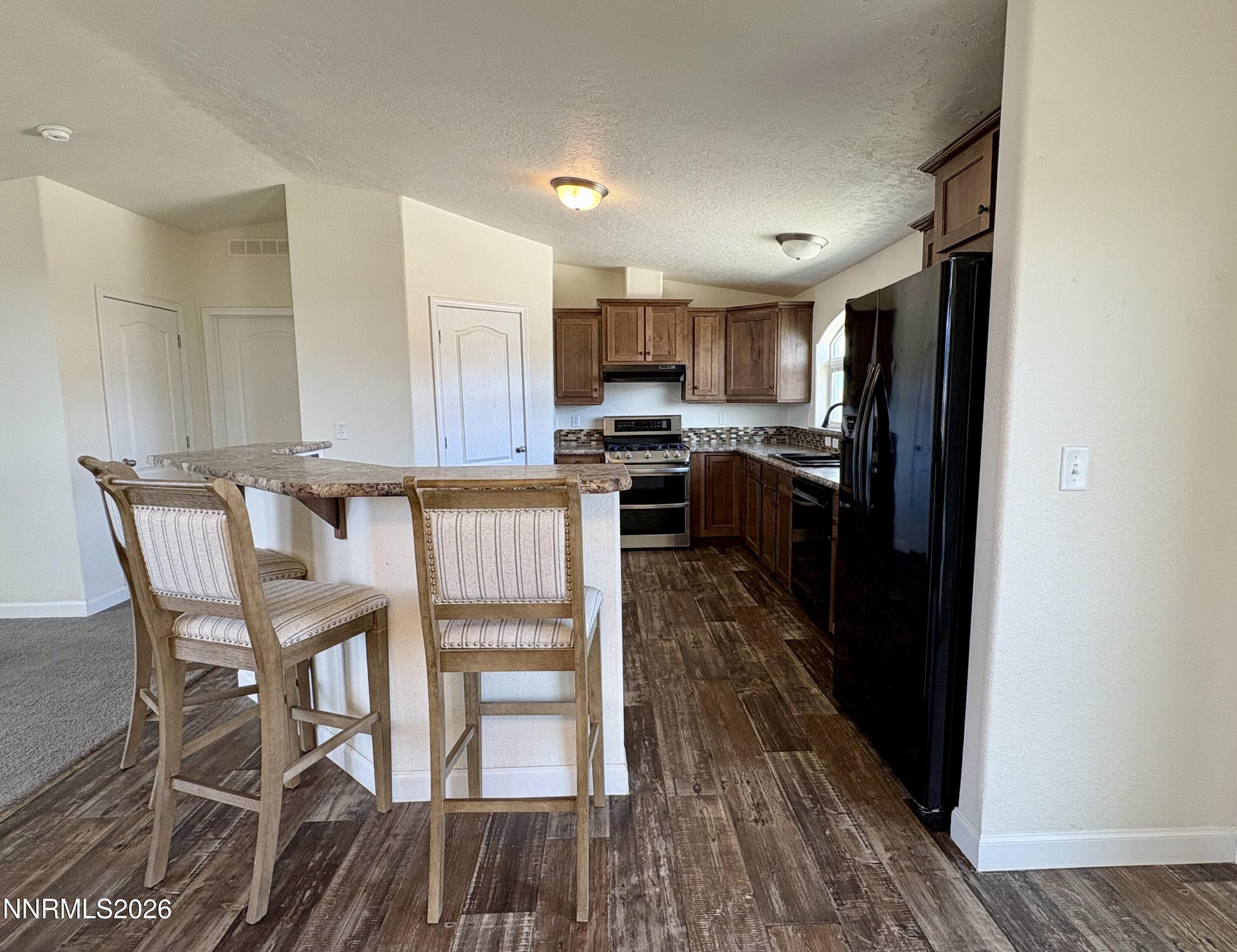 1415 Van Diest Road Winnemucca, NV 89445 - Photo 10 of 34 a kitchen with kitchen island wooden floors and stainless steel appliances
