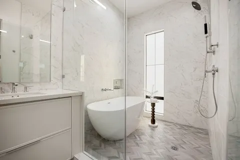 a bathroom with a white bath tub a sink and a large mirror