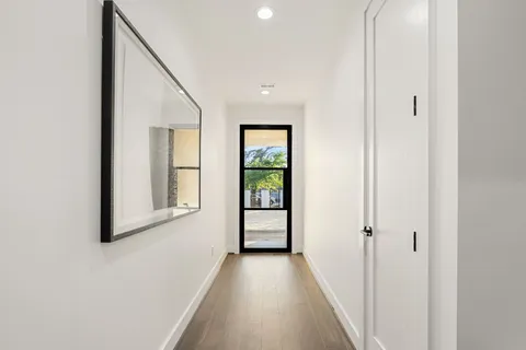 a view of a hallway with wooden floor and windows